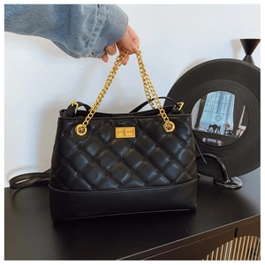 Detail of black quilted PU leather tote bag with gold metal lock and chain strap