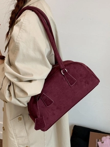 Chic burgundy Boston barrel shoulder bag in suede texture styled with a beige trench coat