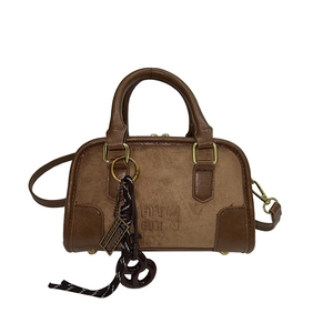 Sac Boston marron en daim et cuir avec chaîne et charms sur fond blanc éclatant