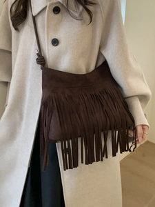 Sac bandoulière en daim marron avec franges bohèmes porté par un mannequin en manteau