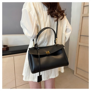 Detail of minimalist black leather tote bag with gold swivel clasp and shoulder strap