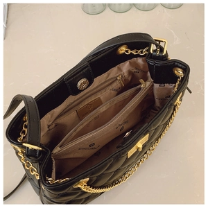 Detail of black quilted tote bag interior with multiple compartments and golden hardware