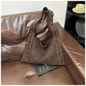 Detail of wide shoulder strap with double-row metal eyelets on vintage brown suede bag