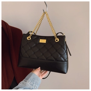 Detail of black quilted tote bag with gold twist lock and metallic chain handle