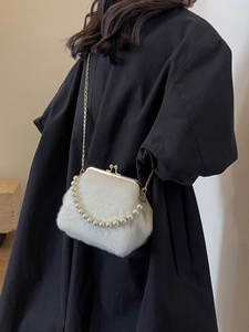 Weiße Kunstfell-Clutch mit Perlengriff und Goldkette getragen von einem Model
