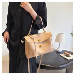 Detail of beige soft leather handbag featuring gold twist lock and adjustable strap
