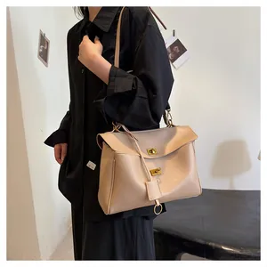 Detail view of a beige minimalist tote bag showing the golden twist lock and adjustable strap