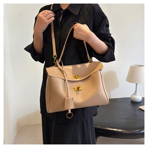 Detail of light brown tote bag featuring textured leather and golden turn-lock closure
