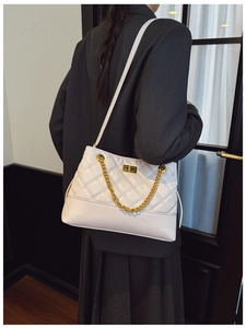 Detailed view of white quilted tote bag with gold chain and turn-lock on a model