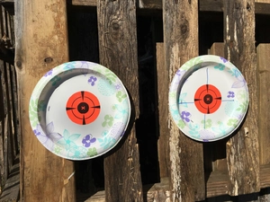 Detail of paper shooting targets with orange bullseye and floral pattern on wood background