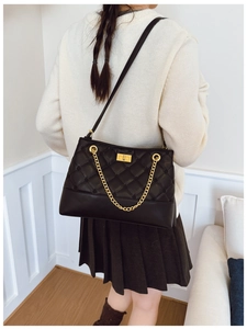Detail of black quilted PU leather tote bag with gold chain and rotary lock clasp