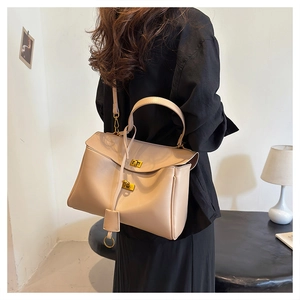 Minimalist beige tote bag with gold metal buckle and strap shown in a modern interior