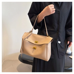 Detail of minimalist beige leather tote featuring elegant gold metal twist lock closure