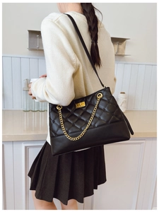 Detailed view of black quilted PU leather tote bag with gold chain and twist lock on model