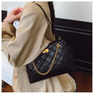 Close-up of diamond quilted texture and golden twist lock on black PU leather bag