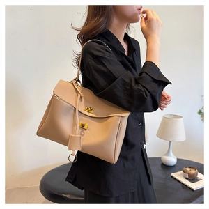 Close-up of minimalist beige leather underarm bag with unique golden double-knob lock detail