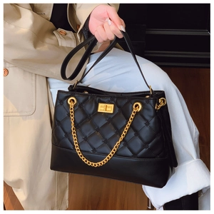 Detailed close-up of black quilted tote bag with golden metal lock and chain strap detail