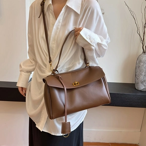 Minimalist deep brown leather tote bag with metallic twist lock shown as a shoulder bag