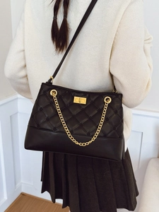 Chic black quilted tote bag with golden chain strap and buckle in stylish street style