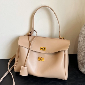 Minimalist beige soft leather tote bag with gold metal buckle and adjustable strap