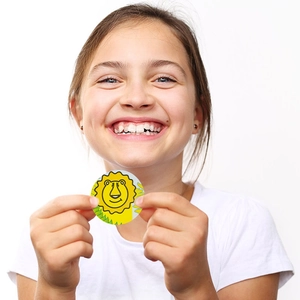 Happy girl holding a round cartoon lion reward sticker with yellow animal design