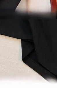 Detail of double-stitched cuffs and hem on an oversized black cotton T-shirt