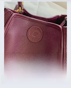 Close-up of burgundy litchi grain leather texture and gold hardware on bucket bag