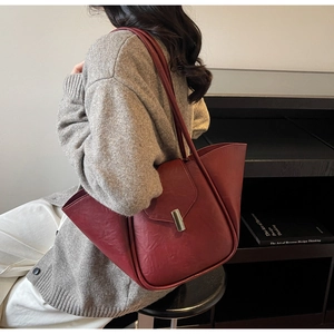 Detail of burgundy shell-shaped tote bag with lychee texture and gold lock hardware