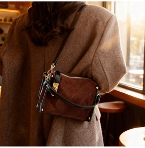 Detail of dark brown quilted suede crossbody bag with gold metallic lock and hardware