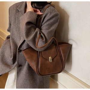 Detail of vintage brown shell tote bag with gold clasp paired with wool blazer