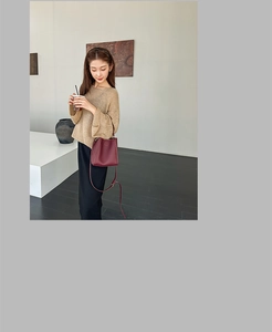 Burgundy bucket bag with lychee pattern on a model in a minimalist indoor setting