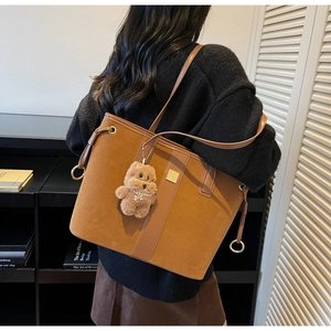 Brown vintage suede tote bag with leather strap and plush bear charm shown on model