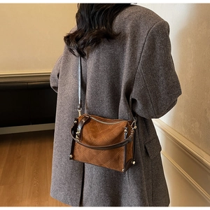Detail of a brown quilted suede handbag with gold metal hardware on a modern coat