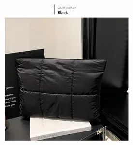 Close-up of black quilted fashion clutch featuring large square embroidery and soft texture