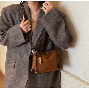 Brown suede crossbody bag with diamond stitching and gold metal lock worn by a model