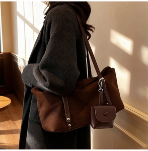 Detail of a large brown suede tote bag with a matching coin purse on a wool coat