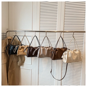 Detail view of stylish pleated cloud bags in six colors hanging on a minimalist rack