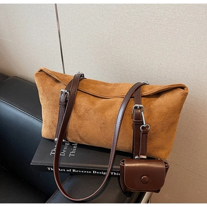 Detailed close-up of brown matte tote bag with adjustable straps and mini coin purse charm