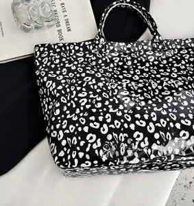 Vue de haut d'un sac cabas brillant à motif léopard noir et blanc avec texte TOTE BAG