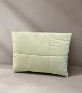 Detail of light green quilted nylon laptop sleeve with magnetic closure and soft texture