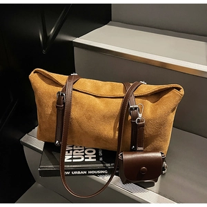 Close-up of caramel frosted tote bag with adjustable leather straps on a grey step
