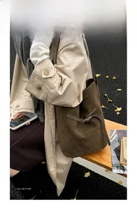Détail d'un sac seau en daim marron foncé avec bandoulière en cuir et style automnal