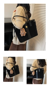 Close-up of black suede tote bag featuring a gold square buckle and plush bear charm