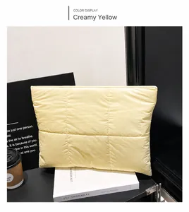 Detail of creamy yellow quilted padded clutch bag with square stitching texture