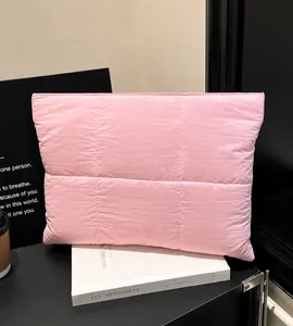 Pink quilted nylon laptop bag displayed on a minimalist desk with books and coffee