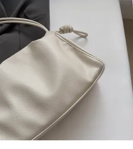 Close-up of creamy white pleated cloud bag showing detailed lychee grain leather texture