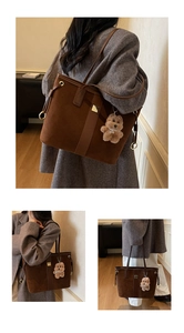Detail of dark brown suede tote bag featuring a leather strap and plush bear charm decoration
