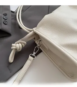 Detail of premium lychee leather texture and silver metal hardware on a cloud bag