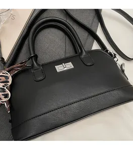 Détail d'un sac bowling noir avec fermoir rotatif et charm cœur motif léopard