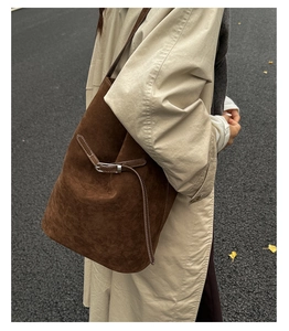 Texture détaillée du daim marron foncé sur un grand sac seau minimaliste avec une boucle en métal